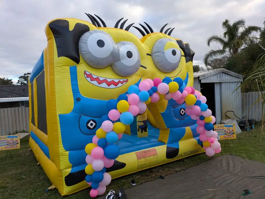 Minions bouncy castle set up behind a pink and blue balloon arch in a family backyard — Perth, WA